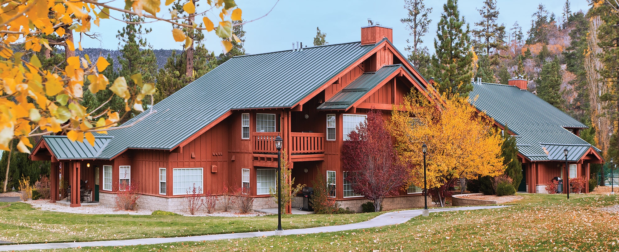 The exterior of WorldMark Big Bear, a cabin-style timeshare resort, surrounded by trees with autumn leaves.