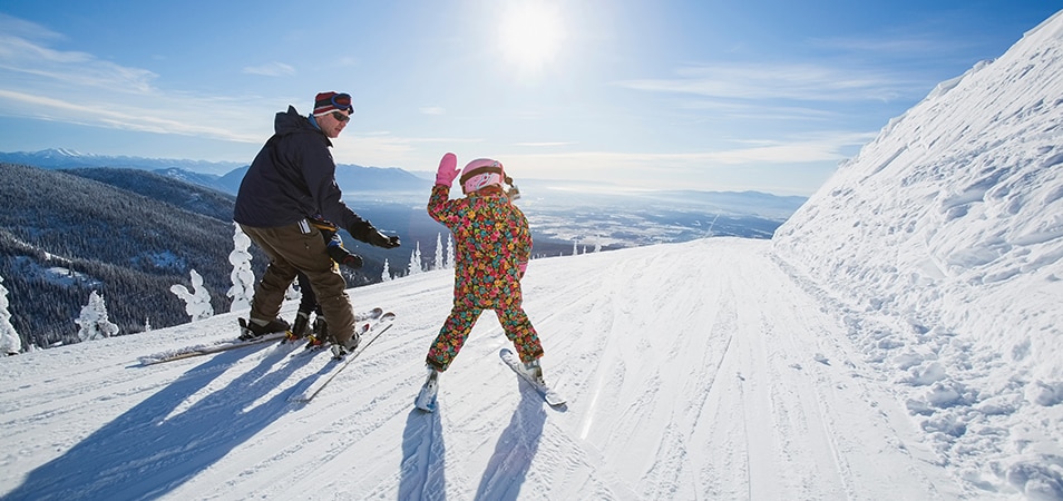 A dad and child skiing together on a snowy mountainside in Pagosa Springs, Colorado. 